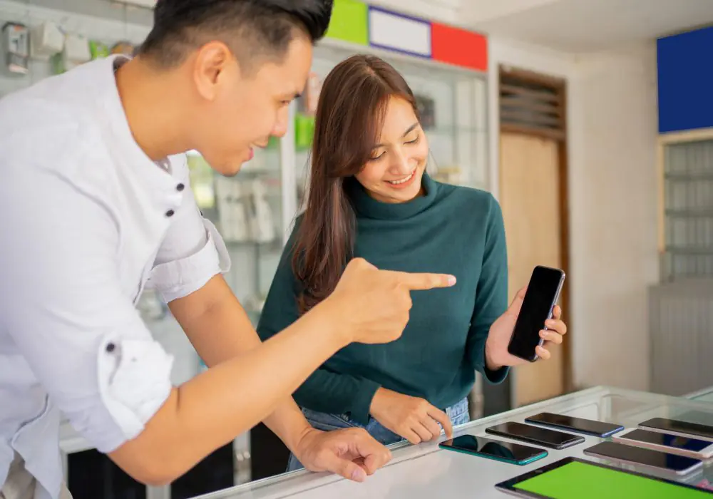 a male shop assistant guiding a female customer using a new mobile phone in a mobile phone shop