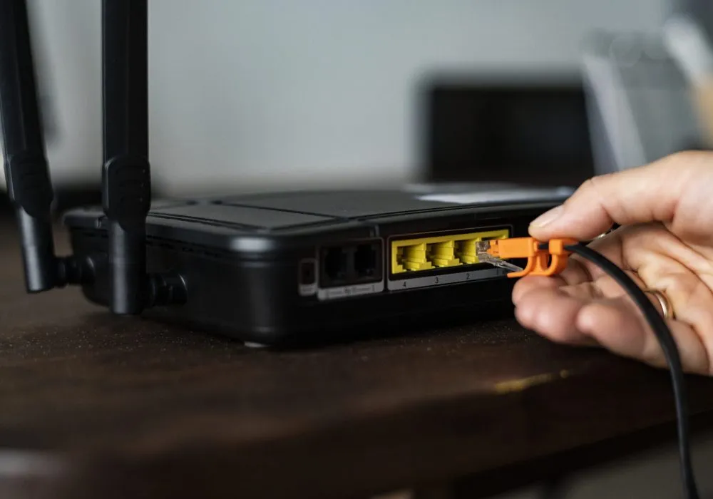 Man plugging in an ethernet cable to a wireless router